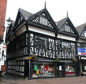 A black-and-white building in a corner position, with two gables to the front and three to the side.
