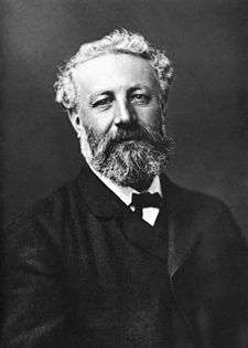 Black-and-white photo of man in formal dress with unkempt hair, mustache and beard.