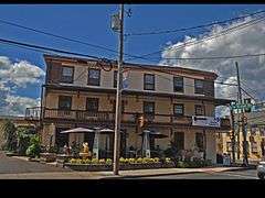 The front of an inn, three stories high, with a balcony on the second floor.