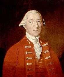 A half-height oil portrait of Carleton. He faces front, wearing a red coat and vest over a ruffled white shirt. His hair is white, and is apparently pulled back.