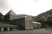 Large dark building with snow-capped mountains at the rear