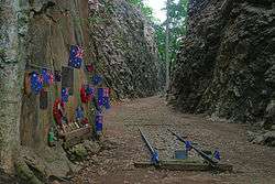 Abandoned railway lines in a deep rocky cutting adorned with memorial flowers