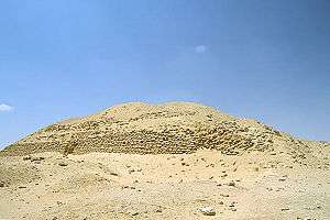 Ruined pyramid raising a few metres from the desert floor, a heap of sand and mudbricks.