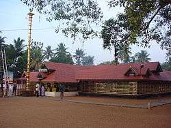 low brown building, with red roof and tall golden pole