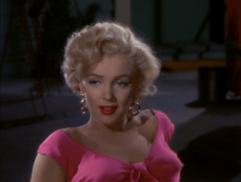 Monroe in Niagara. A close-up of her face and shoulders; she is wearing gold hoop earrings and a shocking pink top.