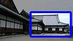 Wooden building with a large hip-and-gable roof, white walls and wooden sliding doors.