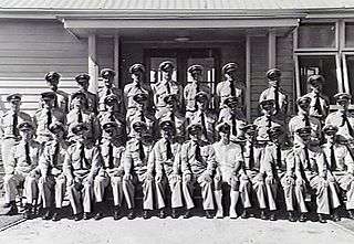 Group portrait of uniformed staff in from of building