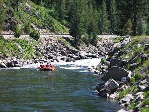 Rafters floating down a small river surrounded by forest