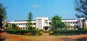 Distant view of modern, low white building with trees in front